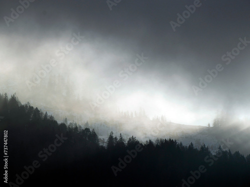 Foggy sunrise on Cross Mountain peak Monte croce sun rays passing through clouds in winter dolomites snow panorama val badia valley
