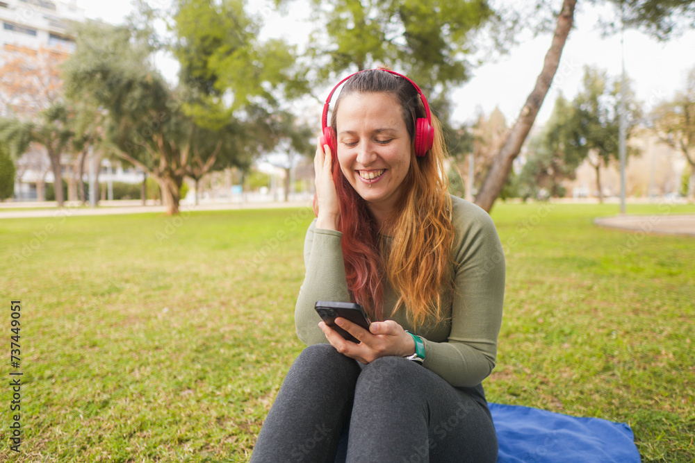 Woman laughing with headphones, using smartphone