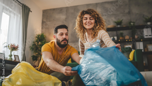 husband and wife recycle at home sorting waste plastic paper and glass photo