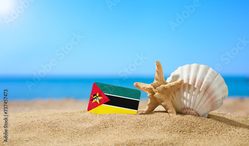 Tropical beach with seashells and Mozambique flag. The concept of a paradise vacation on the beaches of Mozambique