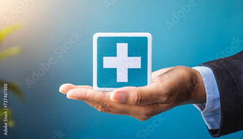 Clean background with hand holding plus sign symbolizing healthcare industry vitality. Caption space for insurance concepts