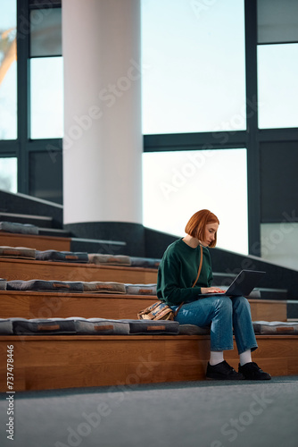 Young woman using laptop in lecture hall at university.