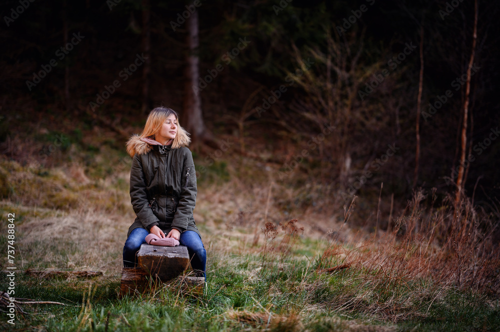 Contemplative Young Woman Sitting on a Wooden Bench in the Forest Contemplative Young Woman Sitting on a Wooden Bench in the Forest