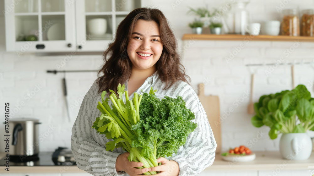 fat overweight smiling young woman with a bunch of greens on the background of a white kitchen, proper nutrition, salad, celery, weight loss, lifestyle, health, girl, food, cooking