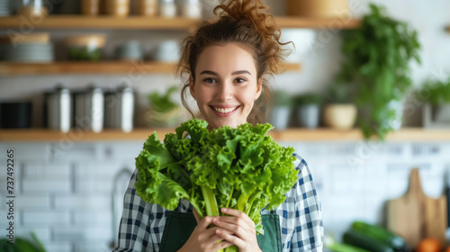 beautiful smiling young woman with a bunch of greens on the background of a white kitchen, proper nutrition, salad, celery, weight loss, lifestyle, health, girl, food, cooking