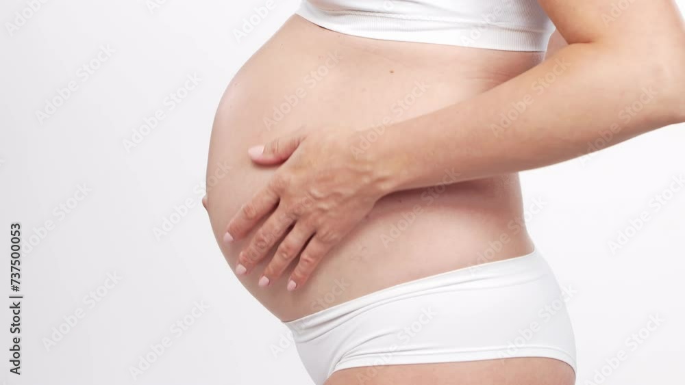 Young, happy and healthy pregnant woman in front of white background. Studio video. Baby expectation, pregnancy and motherhood. Young, happy and healthy pregnant woman in front of white background. Studio video. Baby expectation, pregnancy and motherhood.
