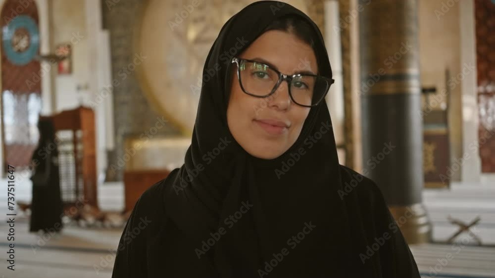 A smiling young woman in a hijab inside a mosque in doha, under soft lighting, conveys tranquility and spirituality. A smiling young woman in a hijab inside a mosque in doha, under soft lighting, conveys tranquility and spirituality.