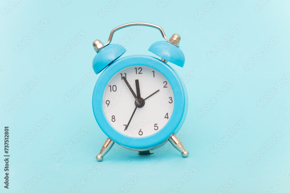 Blue alarm clock on blue background Blue alarm clock on blue background