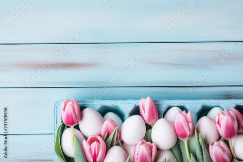 Easter eggs and tulips bouquet in wooden box of wooden pastel blue background. Top view with copy space banner.