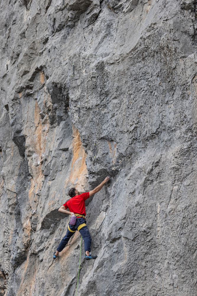 Man in red t-shirt scalded on gray wall, playing sports, reaching limit Man in red t-shirt scalded on gray wall, playing sports, reaching limit