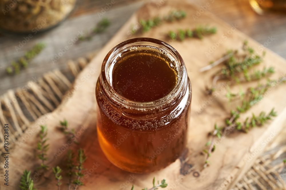 A jar of thyme syrup on a table A jar of thyme syrup on a table