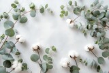 Creative floral background featuring fluffy cotton flowers and delicate eucalyptus twigs on a light gray backdrop perfect for a flat lay flower comp