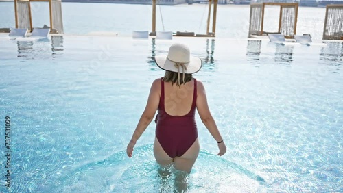 A young woman enjoys summer in a swimming pool, showcasing leisure and beauty in a luxurious resort. photo