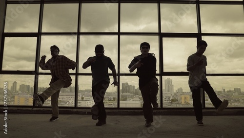 Silhouette shot of skilled choreographer group dancing together with sky scrapper, cityscape background. Young hipster team dancing performance. Sepia filter. Shadow. Outdoor sport 2024. Endeavor.