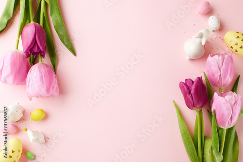 Fototapeta Naklejka Na Ścianę i Meble -  Pink petals and Easter prep. Top view of elegant pink tulips accompanied by a patterned egg and tiny confetti sparkles on light pink backdrop for a joyful Easter greetings