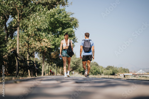 Active couple enjoys outdoor fitness in park. Challenging exercises, stretching muscles. Inspiring others for healthy lifestyle. Summertime recreation with positive results.