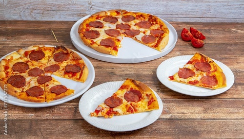Pizza de pepperoni. Fatias de pizza pepperoni em um grupo de pratos brancos sobre uma mesa de madeira. photo