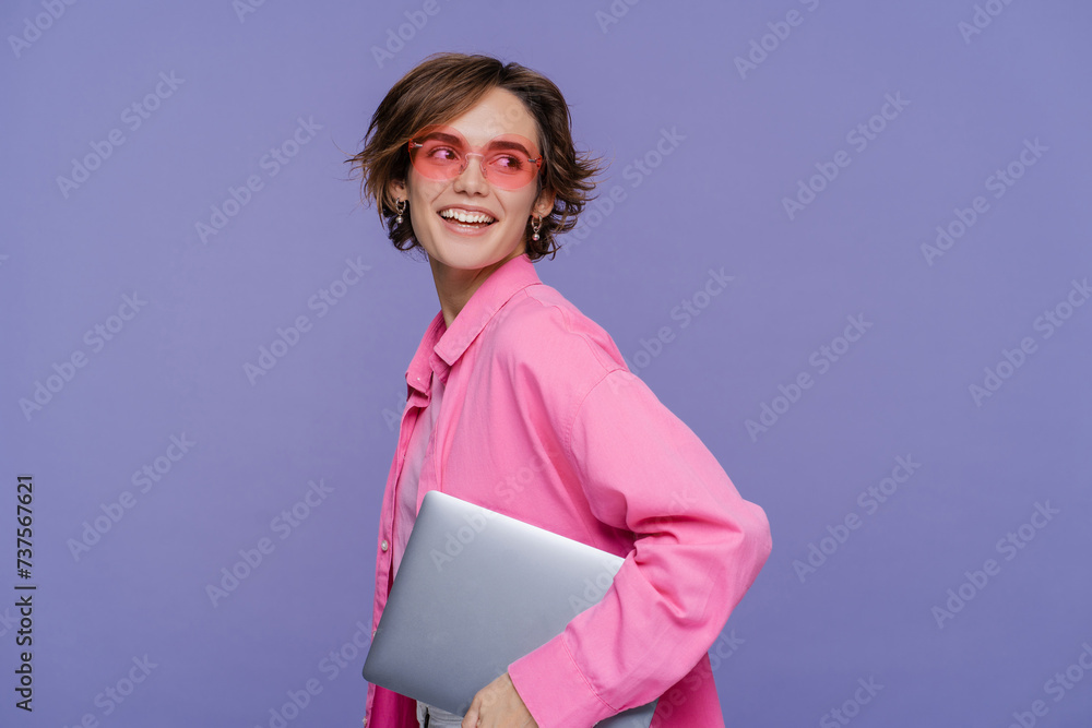 Obraz premium Portrait of beautiful smiling woman using laptop wearing stylish pink clothes holding laptop