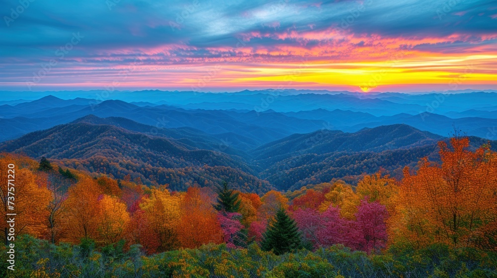 a sunset view of a mountain range with trees in the foreground and colorful foliage in the foreground, with mountains in the background.
