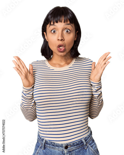 Young Hispanic woman with short black hair in studio celebrating a victory or success, he is surprised and shocked.