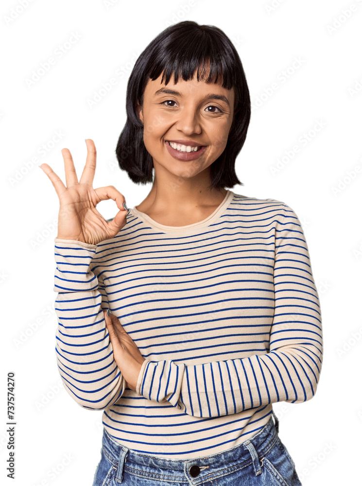 Young Hispanic woman with short black hair in studio winks an eye and holds an okay gesture with hand. Young Hispanic woman with short black hair in studio winks an eye and holds an okay gesture with hand.