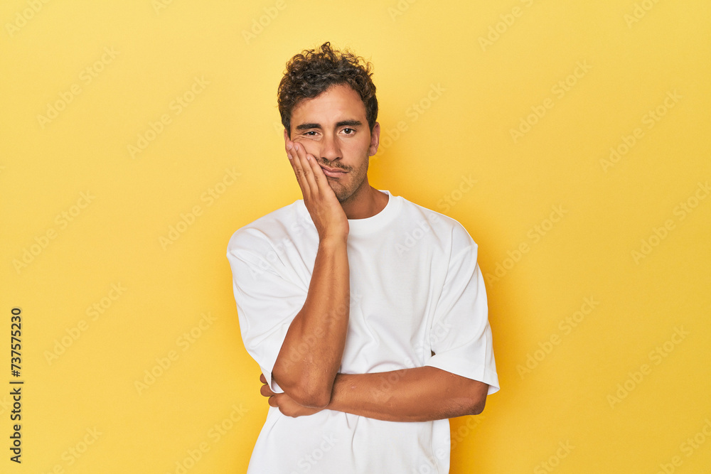 Young Latino man posing on yellow background who is bored, fatigued and need a relax day. Young Latino man posing on yellow background who is bored, fatigued and need a relax day.