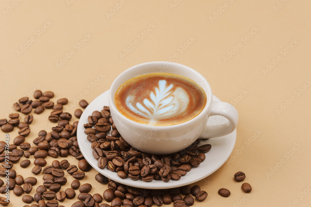 A cup of coffee with coffee art and coffee beans on beige background A cup of coffee with coffee art and coffee beans on beige background