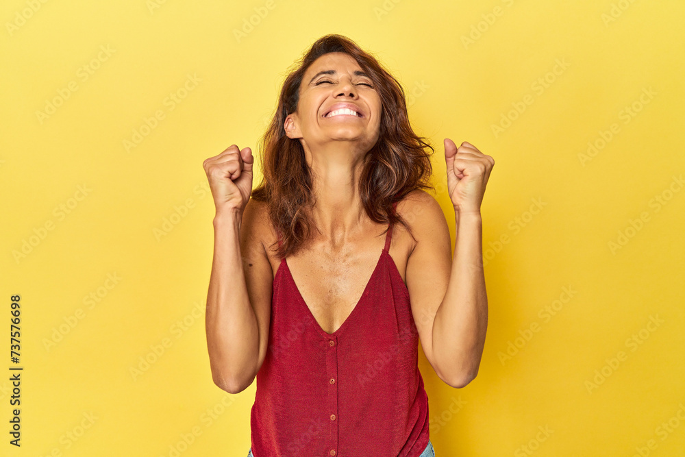 Middle-aged woman on a yellow backdrop celebrating a victory, passion and enthusiasm, happy expression. Middle-aged woman on a yellow backdrop celebrating a victory, passion and enthusiasm, happy expression.