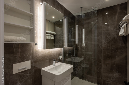 Bathroom interior with brown marble wall and glass shower cabin