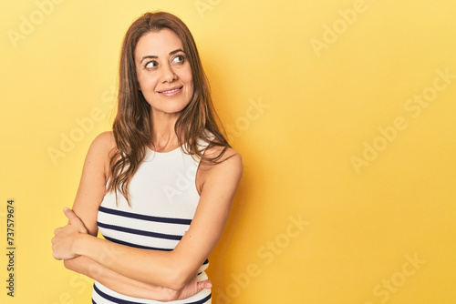 Cheerful middle aged woman posing on a yellow backdrop