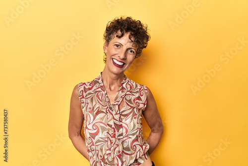Mid-aged caucasian woman on vibrant yellow happy  smiling and cheerful.