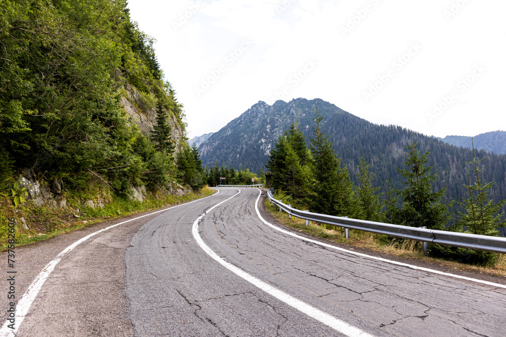 Mountain road in summer. Beautiful curved road, rocks, stones, blue sky with clouds. Landscape with empty highway through the mountain pass in summer. Travel Mountain road in summer. Beautiful curved road, rocks, stones, blue sky with clouds. Landscape with empty highway through the mountain pass in summer. Travel