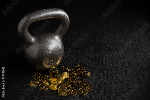 St. Patrick’s Day fitness, silver powder coated iron kettlebell on a gym floor with decorative gold coins with shamrocks

