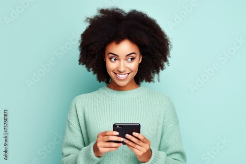 fun young woman wear knitted sweater hold in hand use mobile cell phone look aside on workspace isolated on plain pastel light blue cyan background studio portrait - generative ai