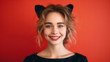 Portrait of happy beautiful young woman with black cat ears isolated on red background with copy space, Valentine's Day, Halloween party cat woman greeting card.
