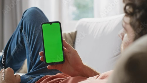 Man hands watching greenscreen cellphone at sofa closeup. Guy holding smartphone photo