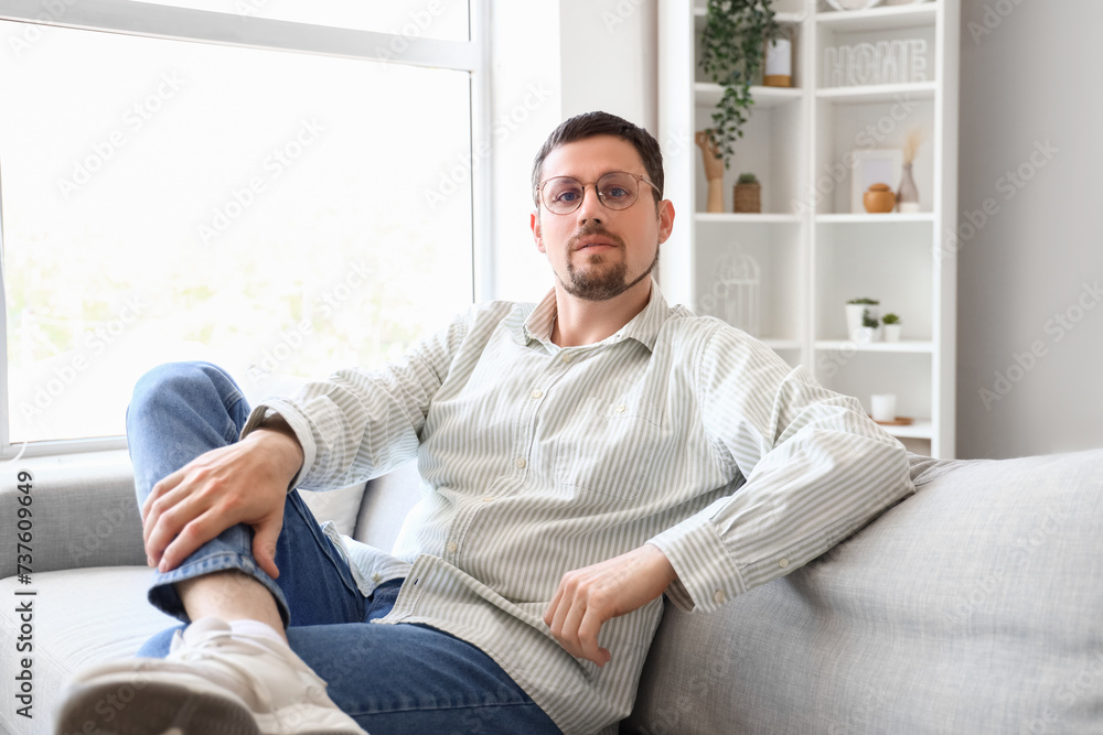 Handsome man in stylish eyeglasses sitting on sofa at home Handsome man in stylish eyeglasses sitting on sofa at home