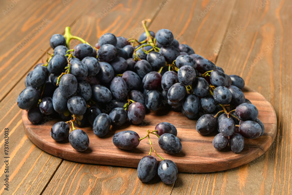 Board with sweet black grapes on wooden background Board with sweet black grapes on wooden background