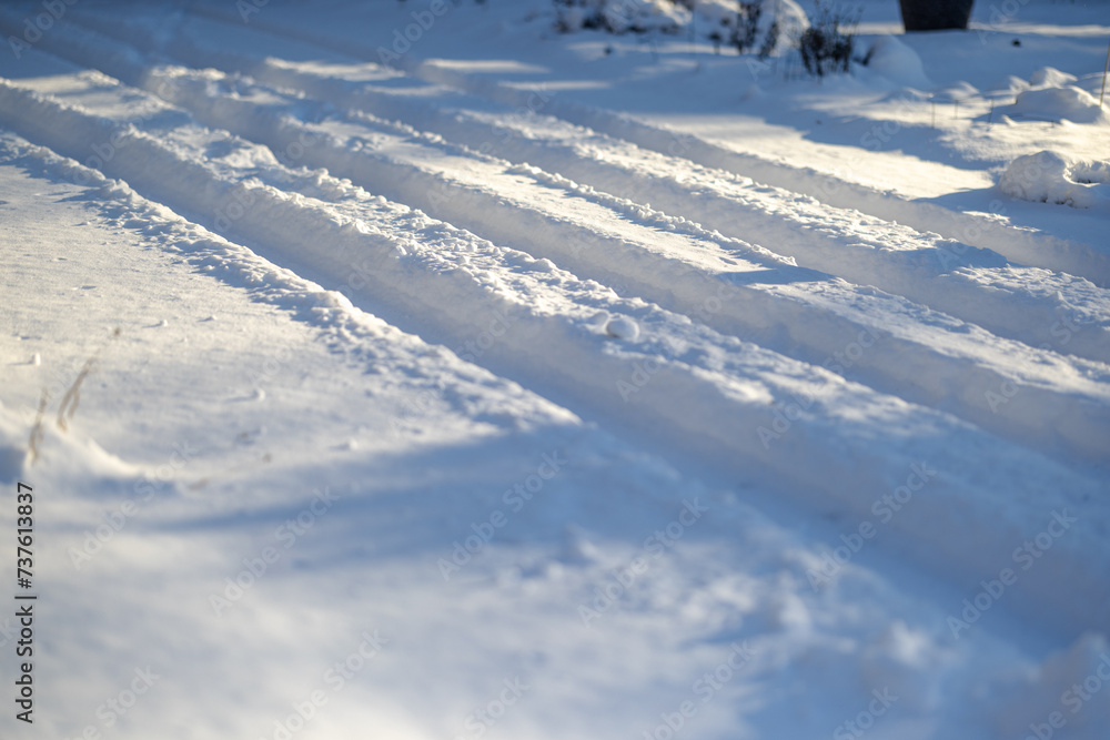 Closeup of car tire tracks through fresh deep snow after Midwest snowstorm