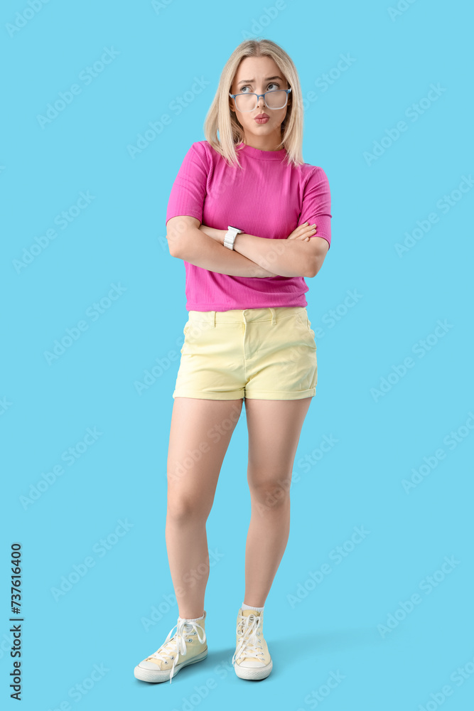 Thoughtful young beautiful woman in eyeglasses on blue background Thoughtful young beautiful woman in eyeglasses on blue background