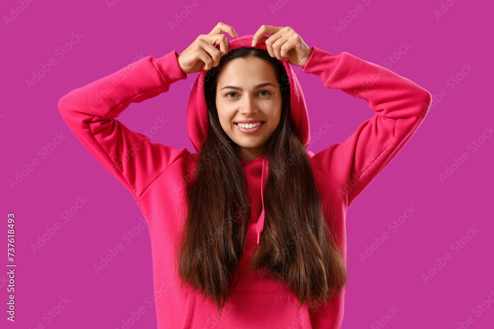 Young woman in fuchsia hoodie on purple background Young woman in fuchsia hoodie on purple background
