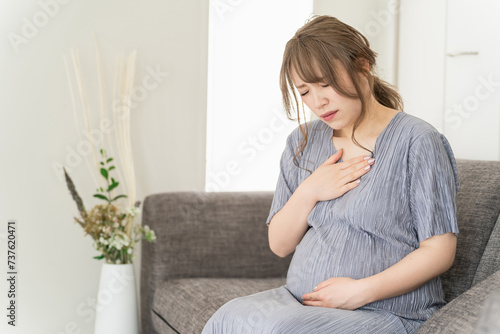 家のソファに座る妊婦・マタニティ（胸焼け・気持ち悪い・妊娠後期）
 photo