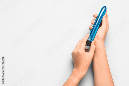 Female hands with vibrator on light blue background