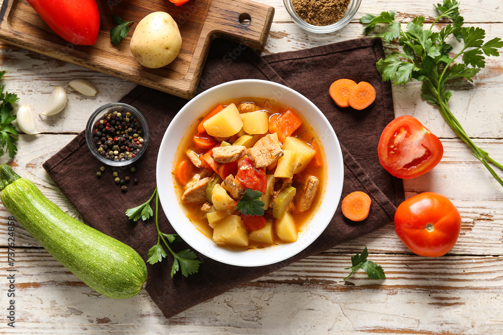 Bowl with delicious beef stew and ingredients on white wooden background Bowl with delicious beef stew and ingredients on white wooden background