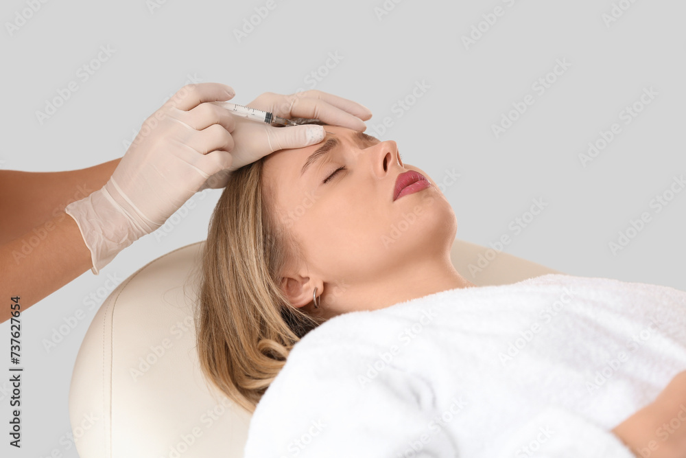 Fototapeta premium Young woman receiving forehead anti-aging injection, cosmetic procedure for wrinkle reduction and skin rejuvenation, this aesthetic procedure aims for skin rejuvenation and a youthful appearance