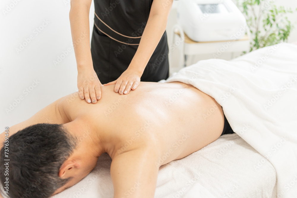 Fototapeta premium メンズエステ・メンズ美容・メンズエステサロンでマッサージを受ける男性とセラピスト