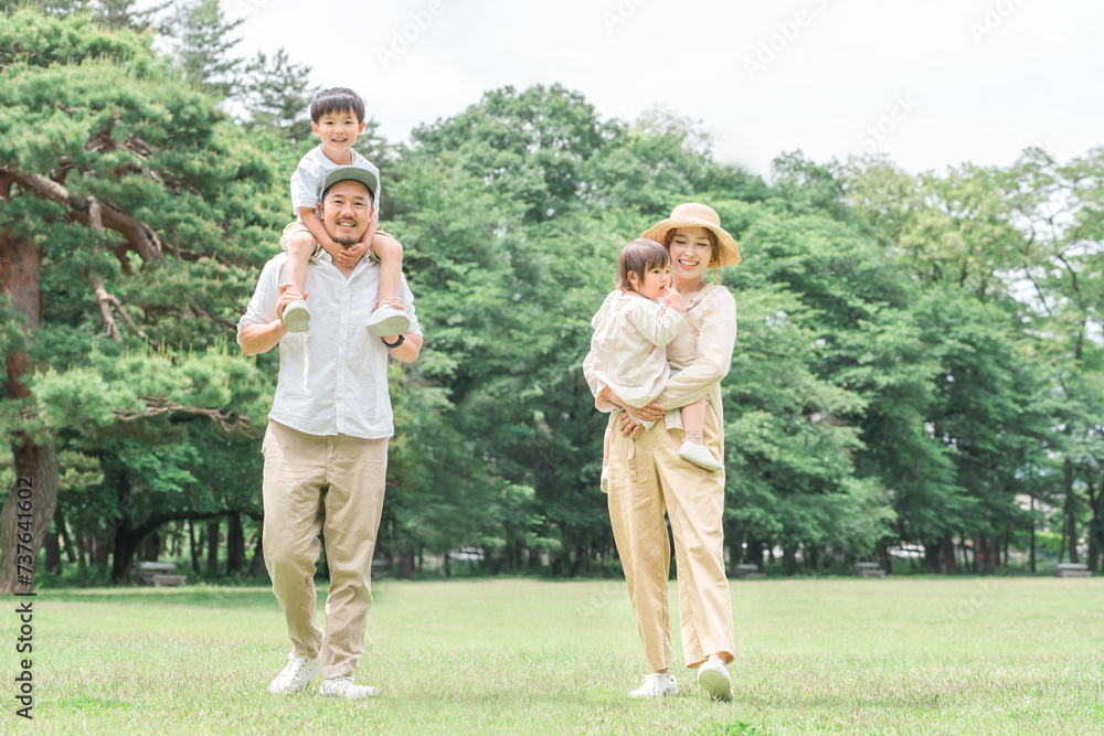 Obraz premium 夏休みに公園を手を繋いで歩く家族・ファミリー(レジャー・アウトドア・ピクニック・キャンプ・思い出)
