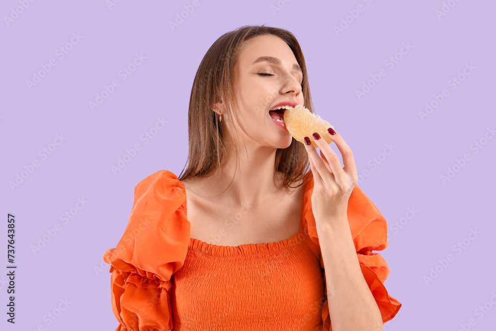 Young woman eating pomelo on lilac background Young woman eating pomelo on lilac background
