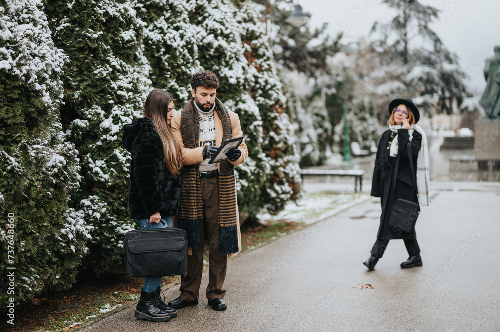 A couple examines a map together, holding luggage in a snowy park, while a cheerful woman walks by, carrying a suitcase and smiling.