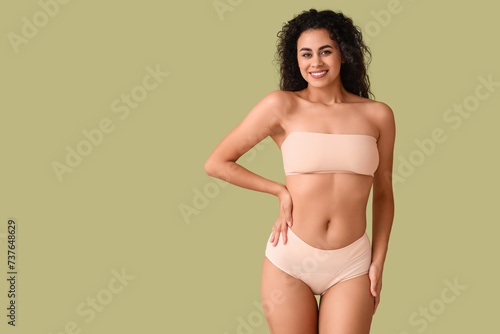 Beautiful young happy African-American woman with stretch marks on her body against green background © Pixel-Shot